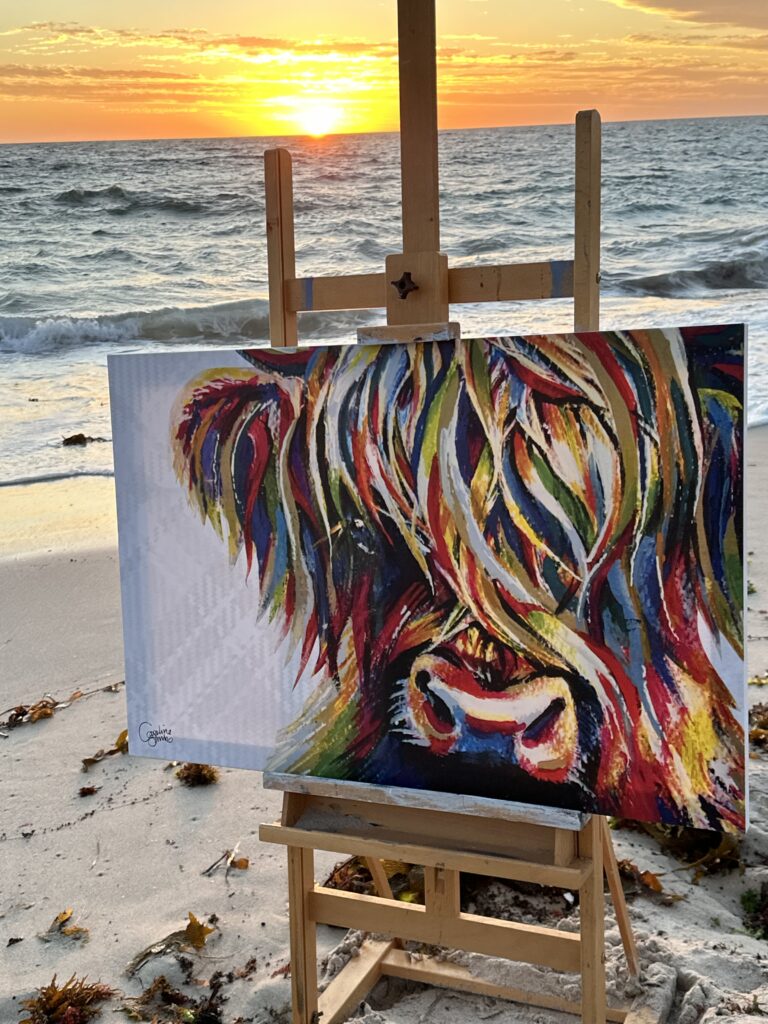 Original Highland cow painting on an easel at sunset on a Perth beach