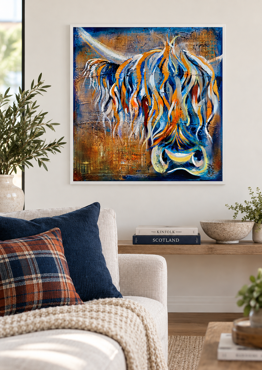 Eamonn Highland coo print framed on a living room wall above a console table