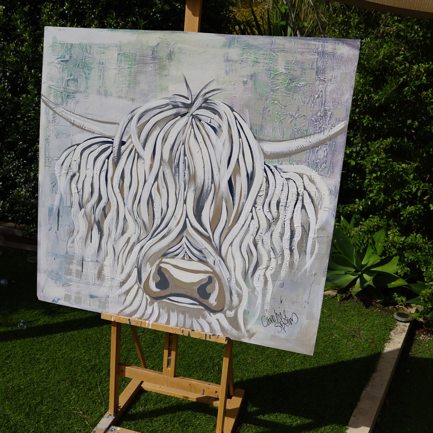 Skye, an original white Highland cow painting by Caroline Speirs, unframed on a wooden easel in the garden in Perth