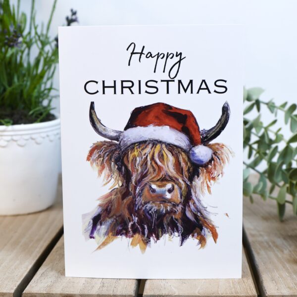 Highland cow Christmas card, ginger coo in a red Santa hat with Happy Christmas lettering, Tartan Paint Scottish Christmas card