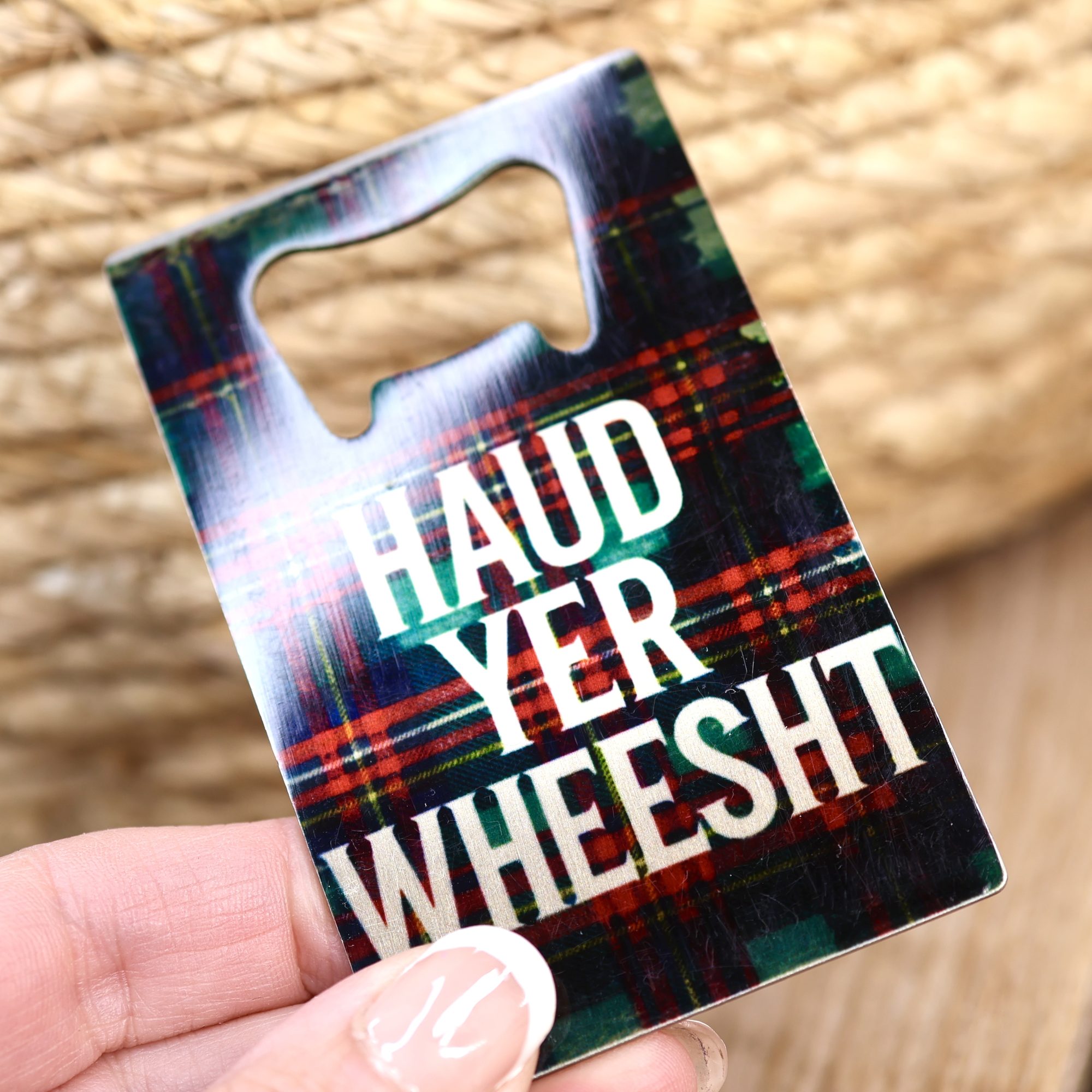 Haud Yer Wheesht wallet sized bottle opener held in a hand