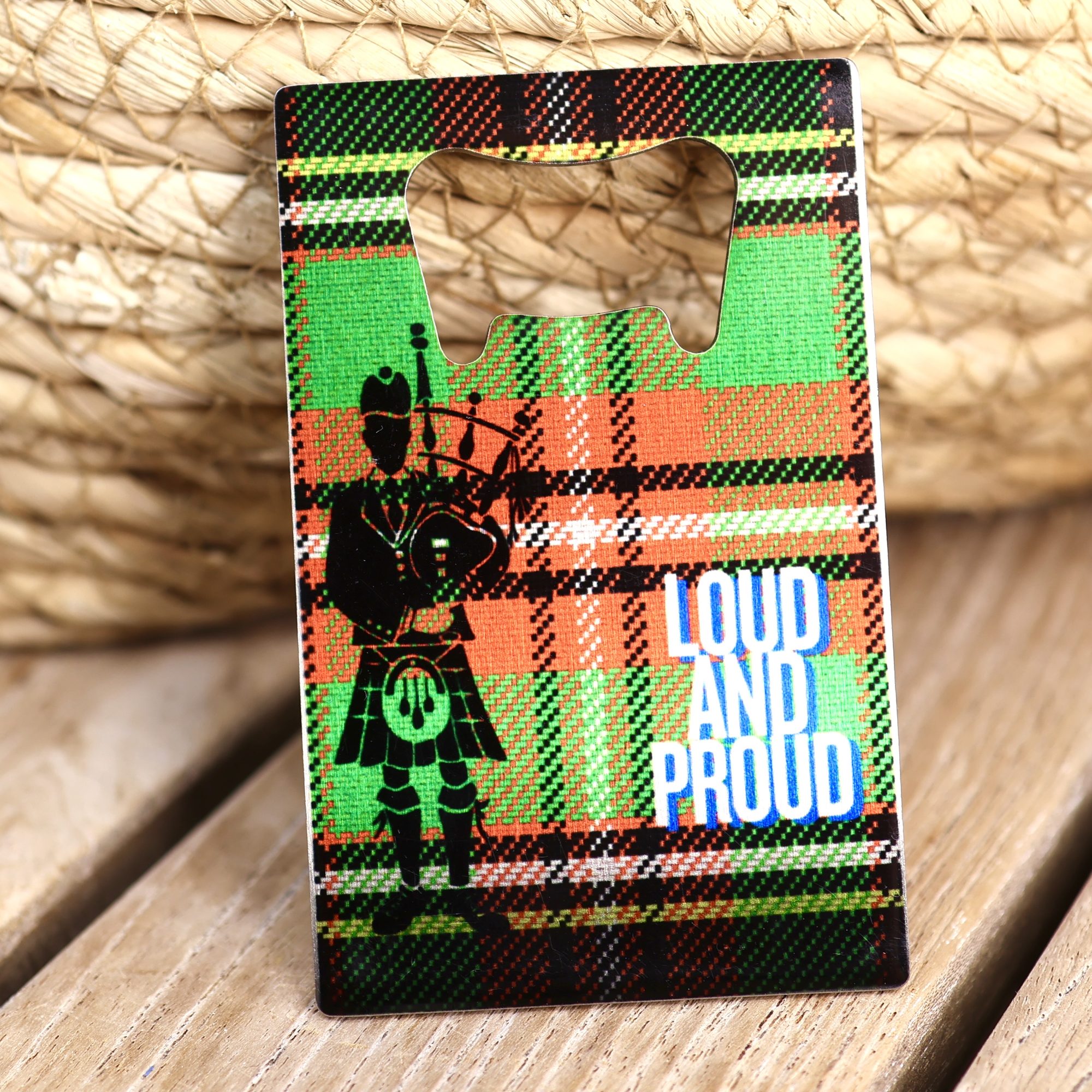 Loud and Proud credit card bottle opener with a piper on green and orange tartan